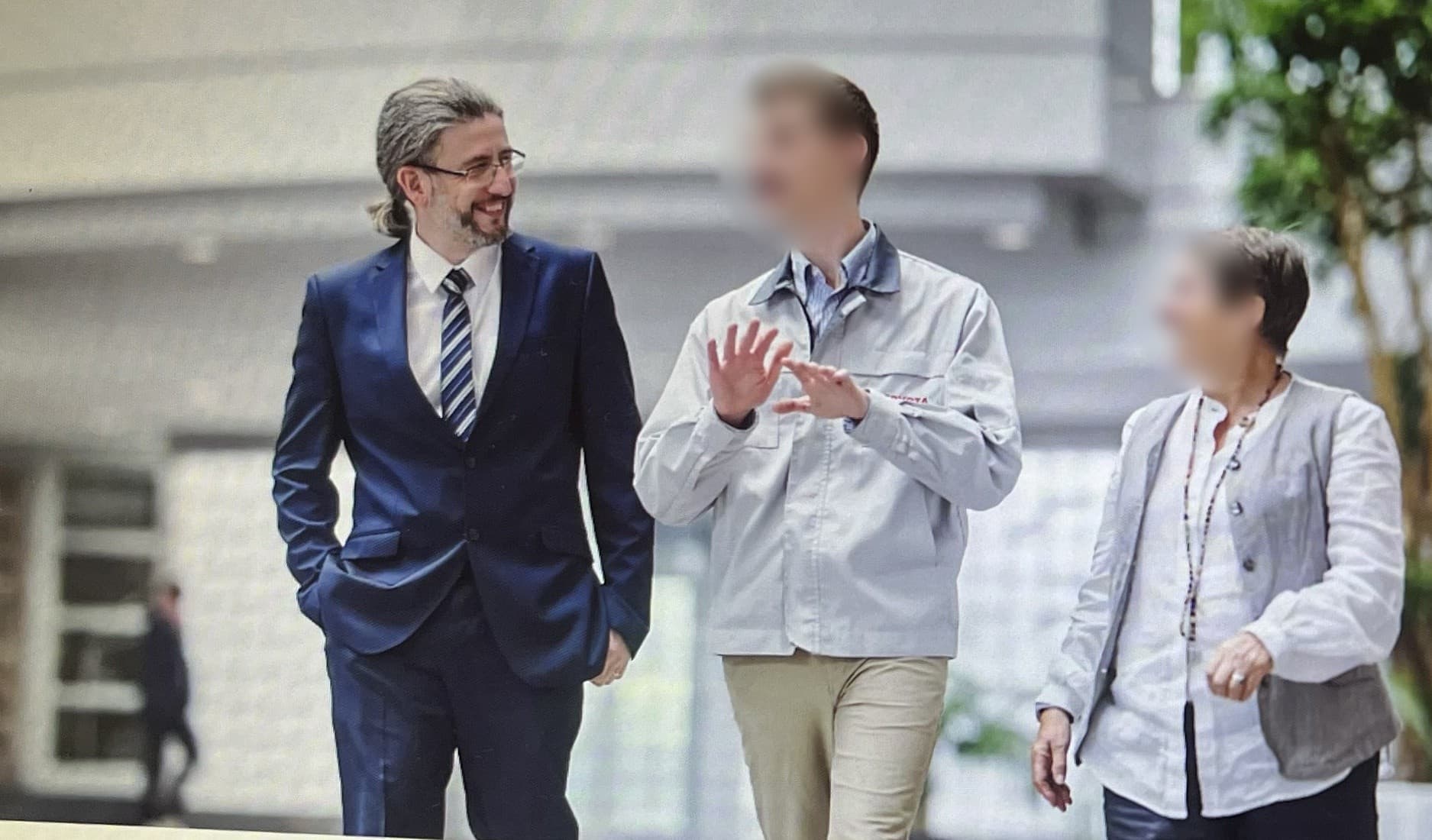 Guven Bircan with colleagues in a workplace setting (faces blurred)